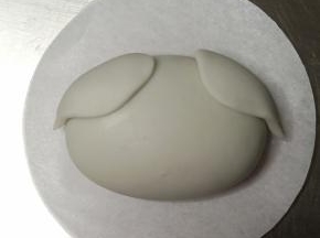 抹少许牛奶粘贴在面团上方两侧，轻轻用手指压平