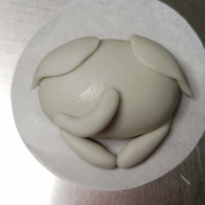 3个1克的小面团揉搓排气滚圆，两个搓水滴，置于面团下方，另一个搓细点的圆柱体，抹少许牛奶粘贴在小象面部