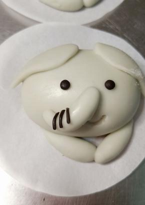 抹少许牛奶粘贴在鼻子中间，搓两粒绿豆大小的黑面团揉圆做眼睛