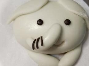 抹少许牛奶粘贴在鼻子中间，搓两粒绿豆大小的黑面团揉圆做眼睛