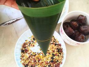 再来做四角粽子，取两片叶子排列整齐，一起卷成漏斗形状的筒