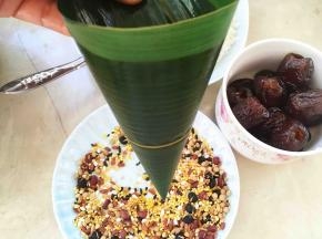 再来做四角粽子，取两片叶子排列整齐，一起卷成漏斗形状的筒