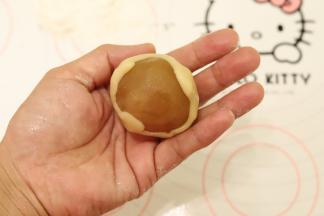 饼皮压成中间稍厚边缘薄的圆片，包住月饼馅，虎口慢慢往上推，收口收紧