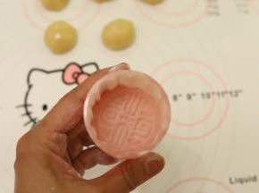 放少许的玉米淀粉到月饼膜内，均匀粘满后倒掉多余的面粉