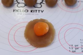 取一小份月饼馅，压平，中间放入蛋黄