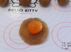 取一小份月饼馅，压平，中间放入蛋黄