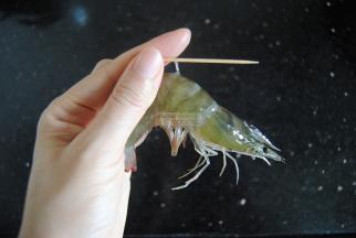 从虾颈数下来第三个关节，用根牙签从这里插入，把虾肠提起拉出丢弃，虾就处理干净了。