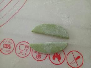 取适量绿色面团揉椭圆状，擀成厚一点的面片，从中间分开