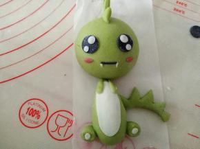 黑色面团搓细条做嘴巴，用白色面团做出恐龙的牙齿来