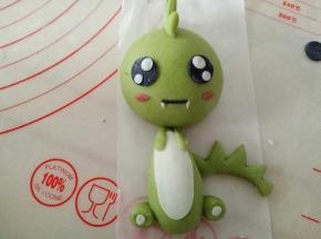 黑色面团搓细条做嘴巴，用白色面团做出恐龙的牙齿来