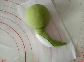 10克的面团搓成一边尖一边粗的椭圆状，尖头朝下，粘到头部，把尾部稍微往一边弯一下，白色面团搓椭圆擀薄片贴身体上作为小恐龙的肚皮，贴侧面哦，我们做的是侧面的恐龙