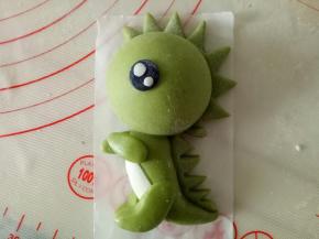 一点白色面团揉竹炭粉作黑色面团，擀薄片压出圆形的眼睛状，白色面团把眼白粘上