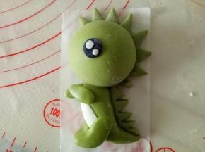 一点白色面团揉竹炭粉作黑色面团，擀薄片压出圆形的眼睛状，白色面团把眼白粘上