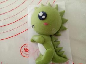 一点点白色面团揉一点点红曲粉作红色面团，把腮红粘上，黑色面团搓细条做嘴巴，再用白色面团做一颗小小的牙齿