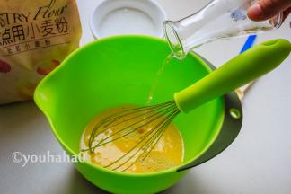 在蛋黄液中加入温水和盐，继续用手动打蛋器搅匀。