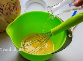 在蛋黄液中加入温水和盐，继续用手动打蛋器搅匀。