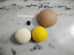 主材料拌匀，揉成光滑面团。揉好后，把白面团分成两份，大概是135克揉入可可粉。
剩下的面团，分出40克当白面团，再分出1克揉入竹炭黑粉，剩下的揉入南瓜粉。

