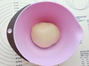 揉成团后再放面板上多揉一会。像做面包一样揉面，揉到能拉出膜，放入盆里盖保鲜膜醒30分钟。