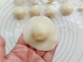 取一份水油皮用手掌按成中间厚边缘薄的皮，包上一个油酥。收口捏紧。