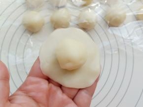 取一份水油皮用手掌按成中间厚边缘薄的皮，包上一个油酥。收口捏紧。