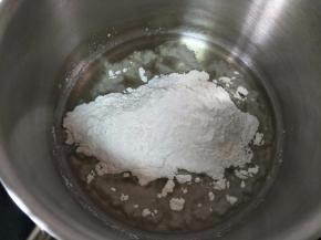 奶锅中倒入玉米油，小火加热到出现细小纹路，关火倒入低筋面粉，搅拌顺滑。