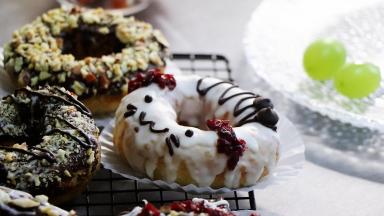 黑白巧克力放到裱花袋中，放到大约45度的温水中，隔水融化。剪口就可以装饰了。每个甜甜圈都挤满巧克力，可以用刮刀辅助抹，顶部撒上坚果碎，蔓越莓干，等巧克力凝固就可以了。