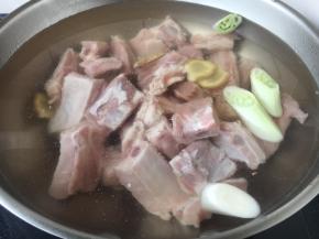 锅里放入小肋排骨，放入凉水，加入姜片和葱段，放入2勺黄酒。