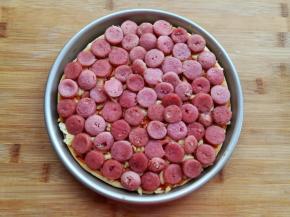 披萨面饼熟后抹上一层番茄酱，撒上适量的马苏里拉芝士碎，铺上香肠片