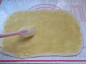 3、	松弛好的油皮面团取出来不用揉，放在案板上，轻轻按扁，用擀面杖韩城长方形大面片，铺上油酥，用刮刀或刮板整理平整，让油酥均匀地平铺在油皮面上，这一步要耐心点哈。