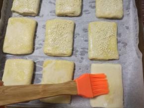 8、	用擀面杖擀长，稍微整理一下，成长方形，放进烤盘中，用小刷子刷上点水，表面撒上白芝麻，静置15分钟。烤箱预热上下火200度15分钟。