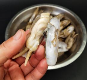 拿起一个蛏子，用剪刀剪去壳。用手把蛏肉旁边的一条黑线撕掉，洗干净，然后在摆入盘中