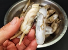 拿起一个蛏子，用剪刀剪去壳。用手把蛏肉旁边的一条黑线撕掉，洗干净，然后在摆入盘中
