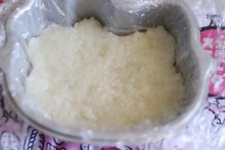 找自己合适的模具，放上保鲜膜。放入1/3的糯米，用勺子压实，会比较粘，可以蘸少量的水来辅助压平实。