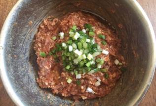 放入葱花，在葱花上淋上1小勺香油，用香油裹住葱花，锁住葱汁，然后再朝一个方向继续搅拌均匀。