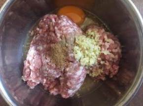 肉馅里放入一个鸡蛋，放入3分之一小勺的十三香，放入3分之一小勺的白胡椒粉，放入2勺的料酒（白糯米酒），放入15g的姜末，朝一个方向搅拌均匀。