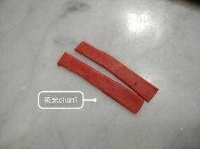 把红面团擀薄，切成宽0.5cm，长6cm的面片。