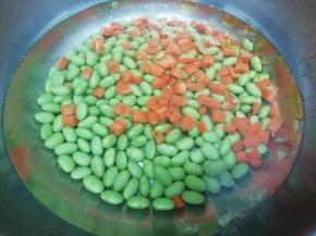 锅里加入适量的水，然后在放入油和盐大火烧开，在把胡萝卜和毛豆放入焯水