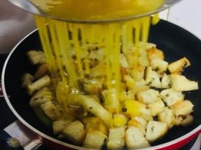 把搅拌好的蛋液通过漏勺，均匀的淋在烤饼丁儿上。