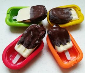 融化后的巧克力倒入一个高一点儿的杯子里，将冷冻成型的蛋奶糕，插入杯子里，立即取出，再放回冰箱冷冻30分钟，巧克力脆皮会很有口感