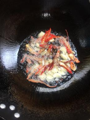 锅烧热倒入适量的油，放入花椒，蒜瓣和红辣椒爆香。