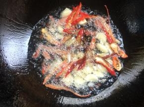 锅烧热倒入适量的油，放入花椒，蒜瓣和红辣椒爆香。