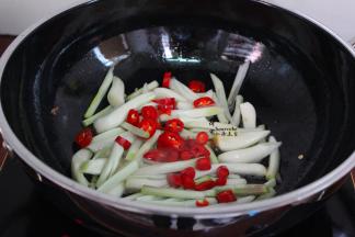 用煎鸭的油，倒入荞头菜、红辣椒，爆炒八成熟；