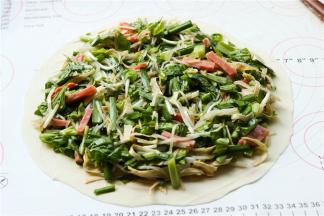 取一个饼胚摊开，放上刚才拌好的蔬菜，边缘留出来不要放。