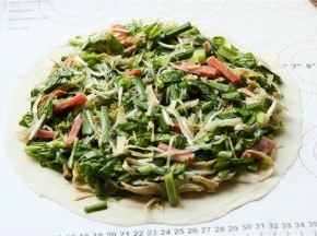 取一个饼胚摊开，放上刚才拌好的蔬菜，边缘留出来不要放。