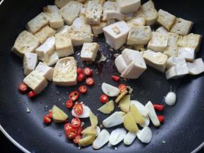 豆腐推至一边，将小米椒、姜、蒜炒香。