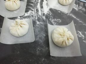 饧好的面团揪成适当的剂子，擀成中间厚，四周薄的圆饼，然后放入适量的馅料包好，底下铺一张油纸