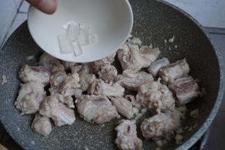 加入料酒，翻炒片刻，倒入冰糖，炒至变色