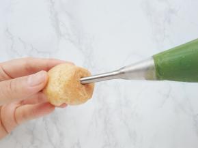 将卡士达奶油放入搅拌盆中用刮刀重新搅拌，让奶油恢复浓稠顺滑的状态，再装入裱花袋，挤入泡芙中。