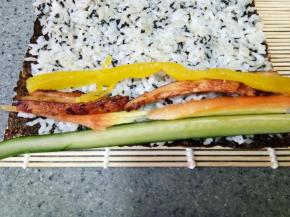 依次放上黄瓜条、胡萝卜条、鸡胸肉条和大根，然后卷起来