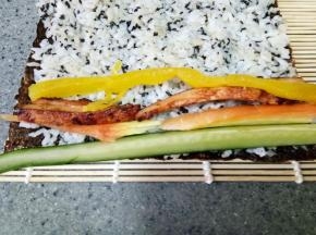 依次放上黄瓜条、胡萝卜条、鸡胸肉条和大根，然后卷起来